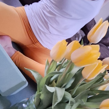 Image of someone doing yoga with yellow flowers on the foreground